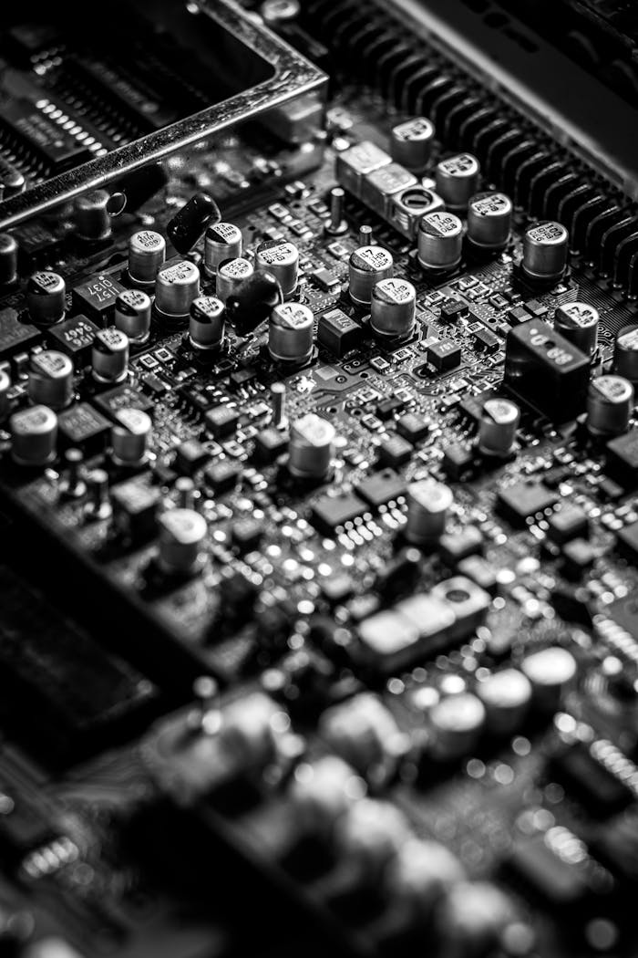 about-06 Detailed black and white close-up of an electronic circuit board with capacitors and transistors.